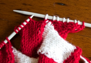 On the right needle: 1 red stitch (the final triangle in the previous tier), 6 picked up white stitches and 1 white ssk (taken from two red) Note that on the left hand needle only 6 of the 8 parallelogram stitches are left.